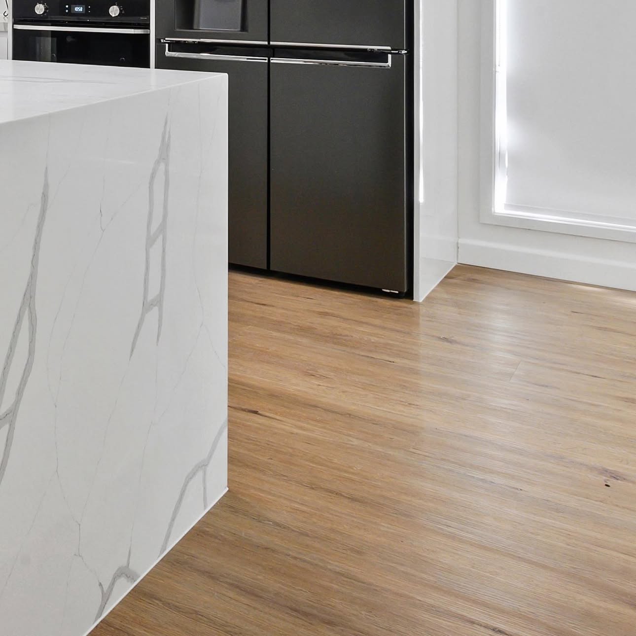 Marble waterfall island kitchen with black appliances